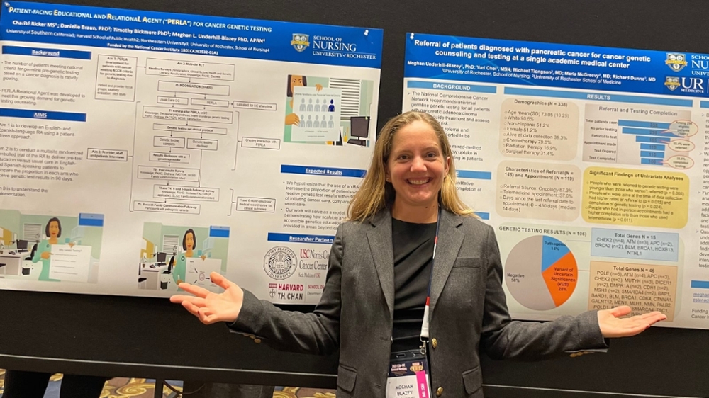 Meghan Underhill-Blazey poses with two conference posters about her research in cancer genetics.